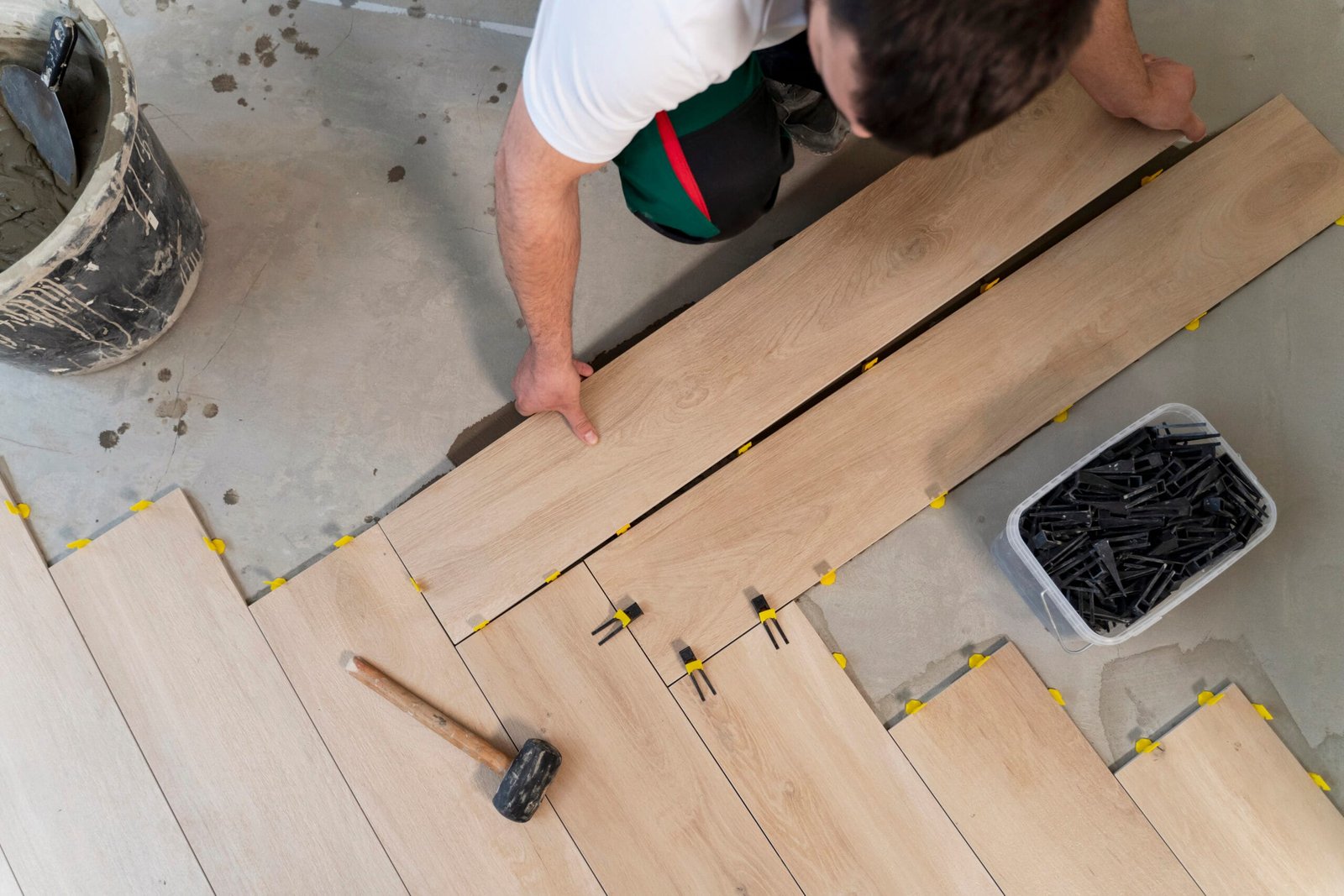 A split image showcasing a homeowner confidently laying vinyl plank tiles (DIY) alongside a skilled flooring installer working on hardwood floors professionally.